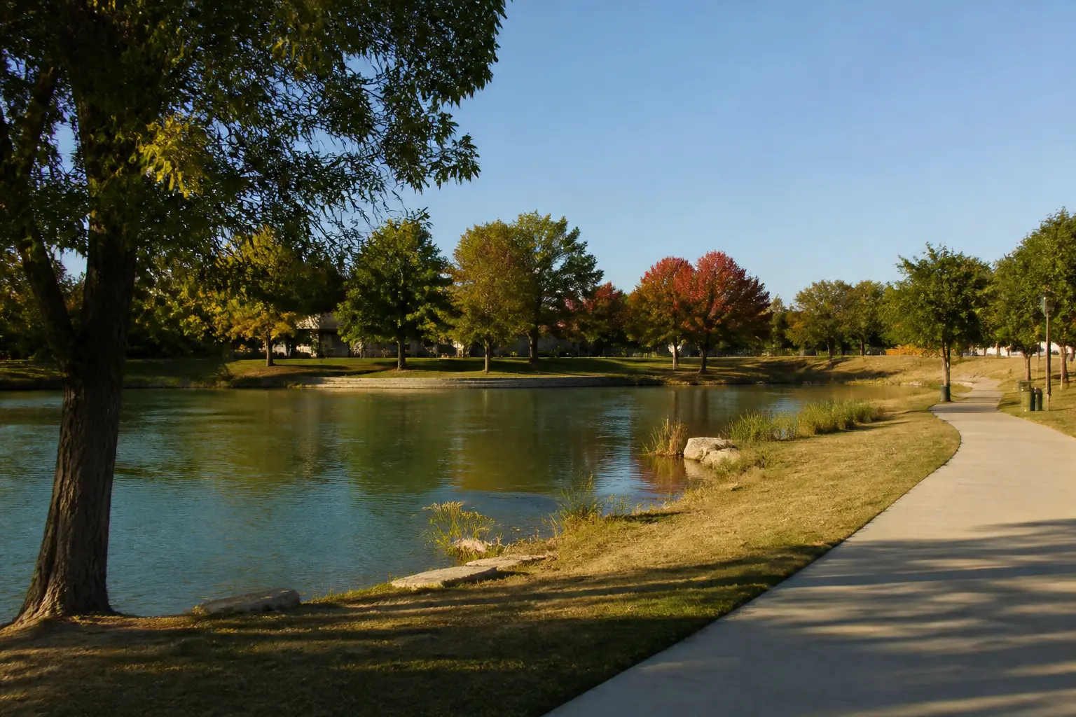 A neighborhood pond with a paved walking path curving along the bank.