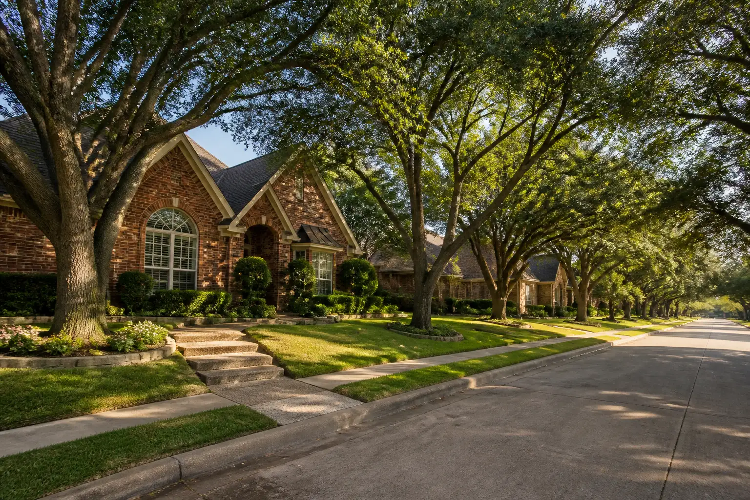 A street of established brick homes shaded by large mature trees.